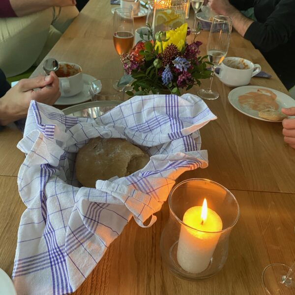 Gedeckter Tisch mit selbgstgebackenem Brot, Eintopf, Blumen und Kerzen