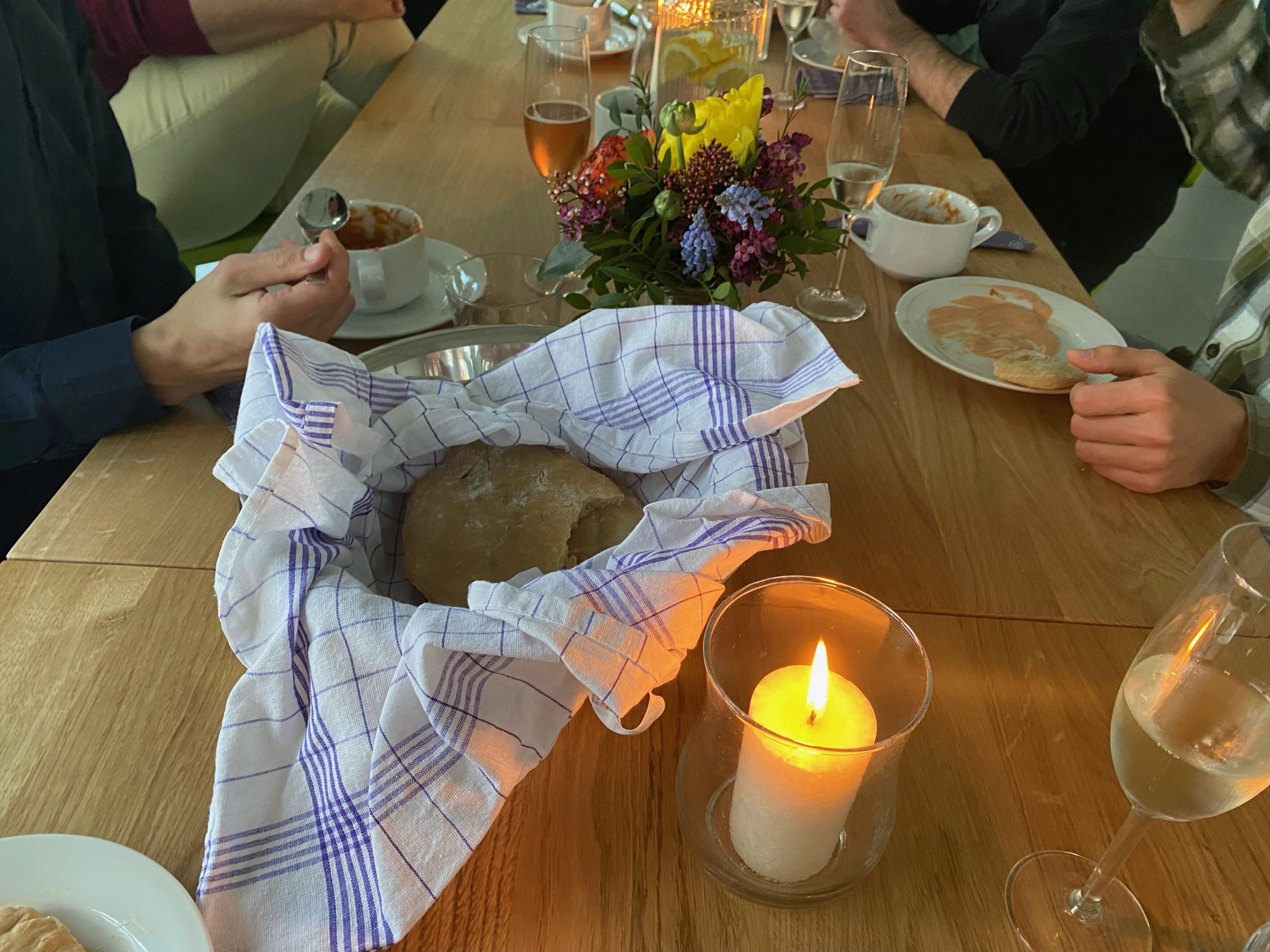 Gedeckter Tisch mit selbgstgebackenem Brot, Eintopf, Blumen und Kerzen